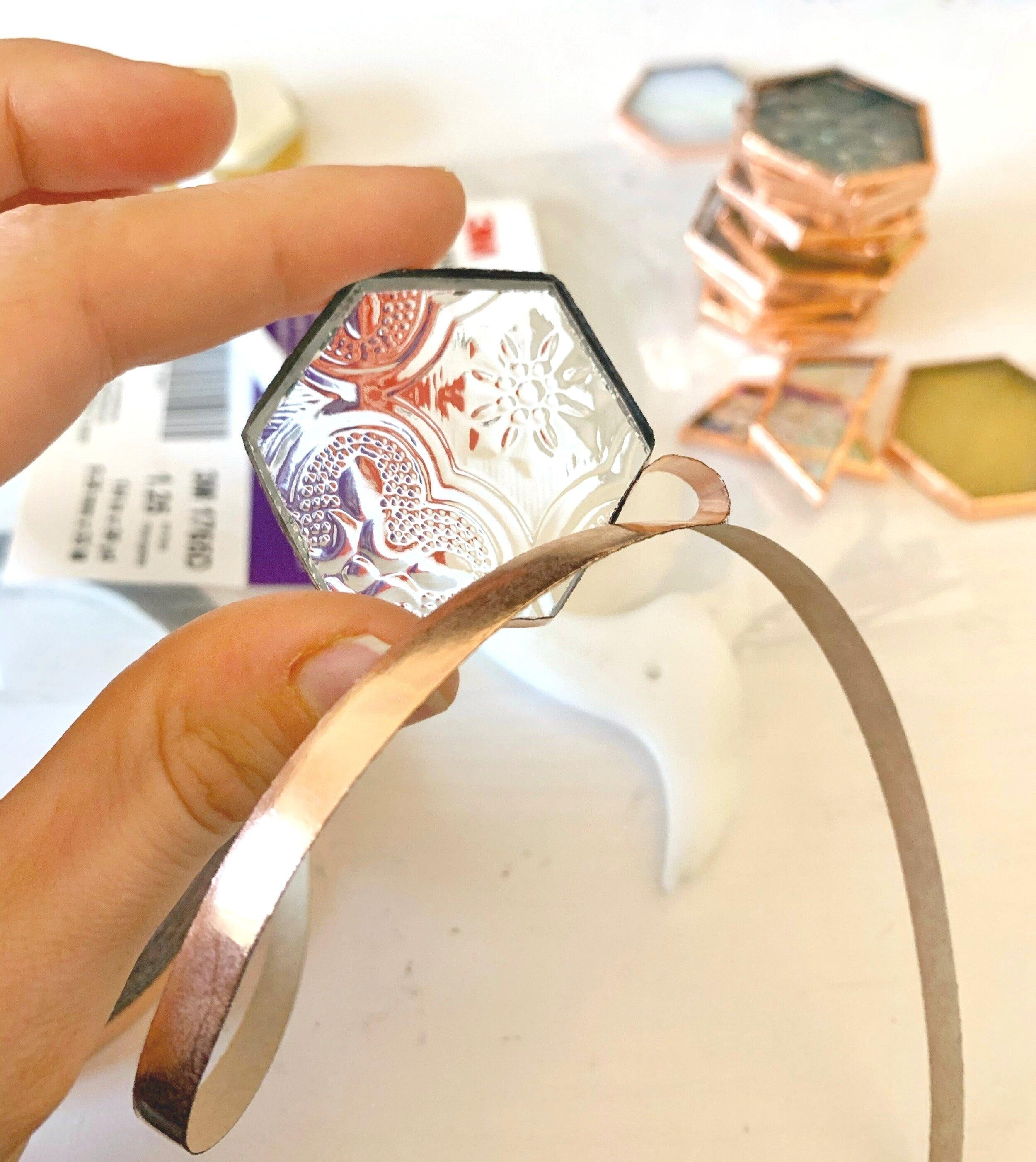 Stained glass foiling with a person holding a small hexagon shape