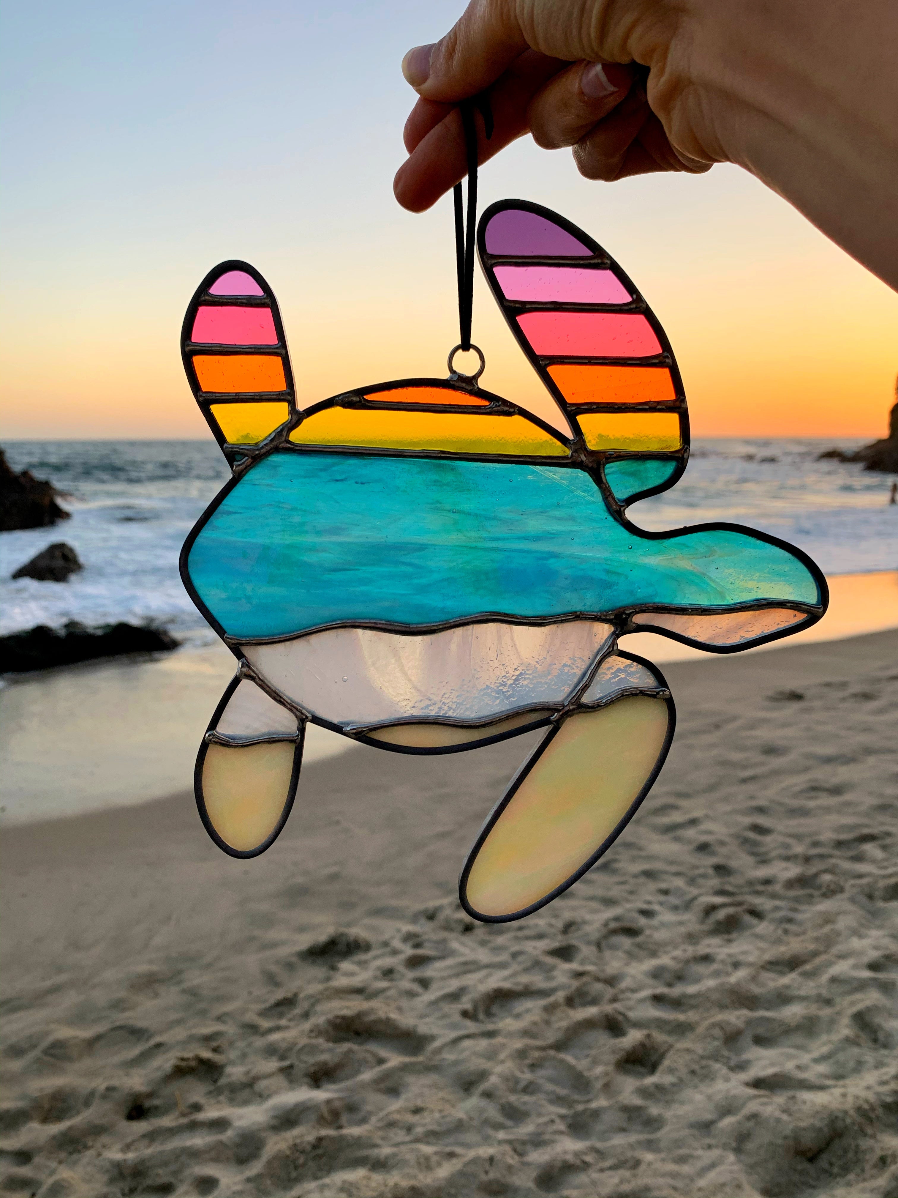 Photo of a stained glass turtle with the beach in the background