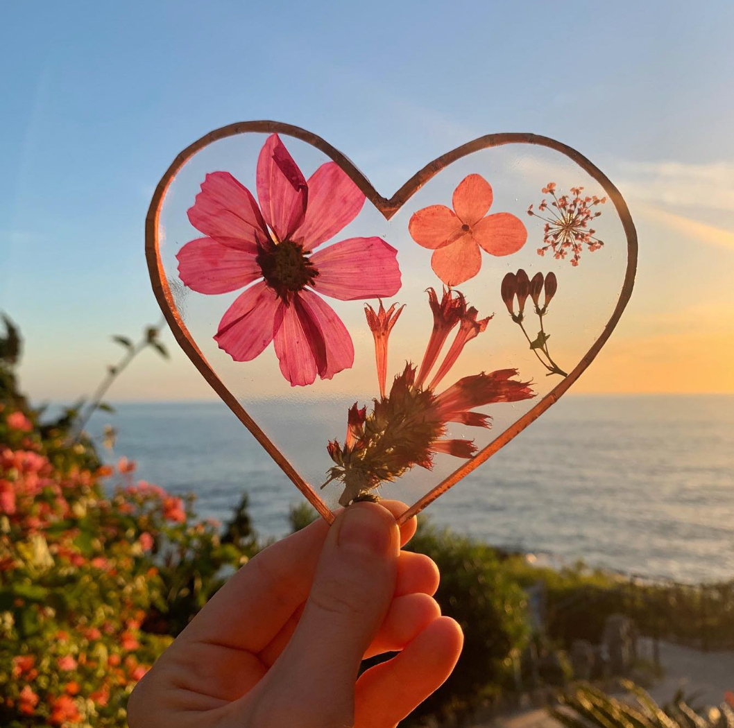 Photo of Stained glass heart with dried flowers in it with a beach in the background