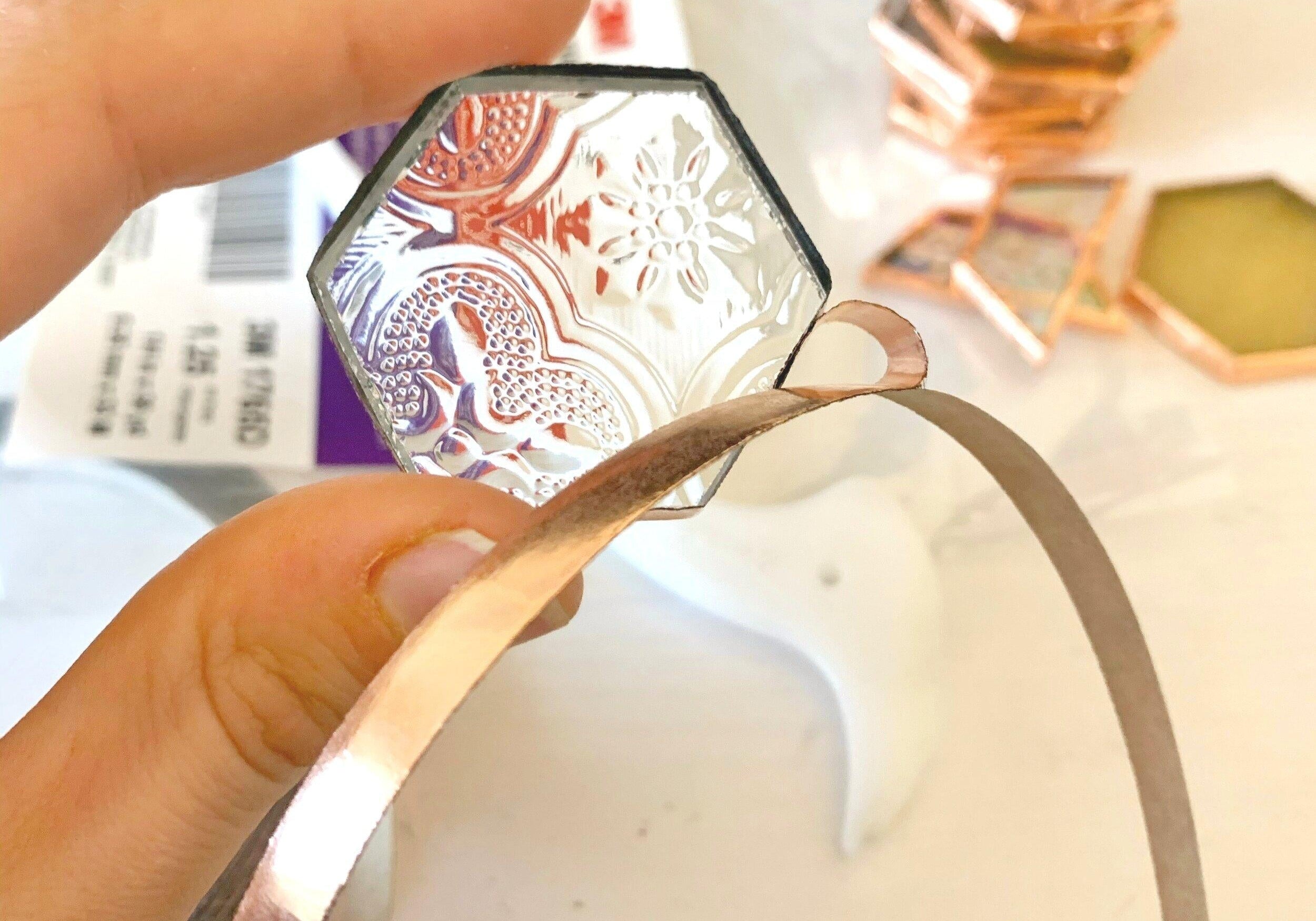 Stained glass foiling with a person holding a small hexagon shape