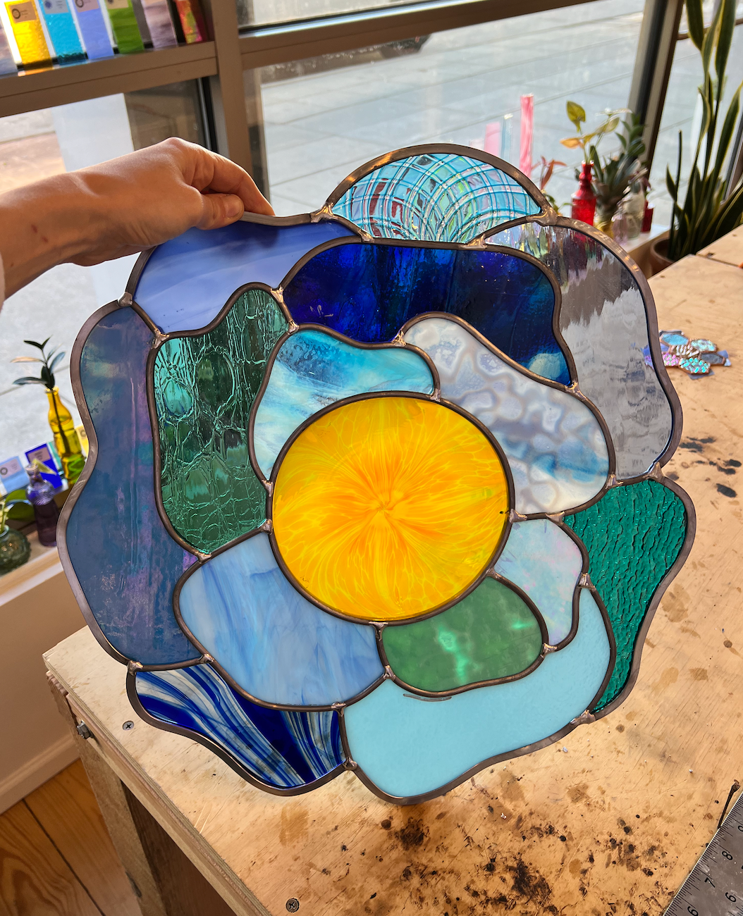 Picture of a large blue stained glass flower with a yellow center 