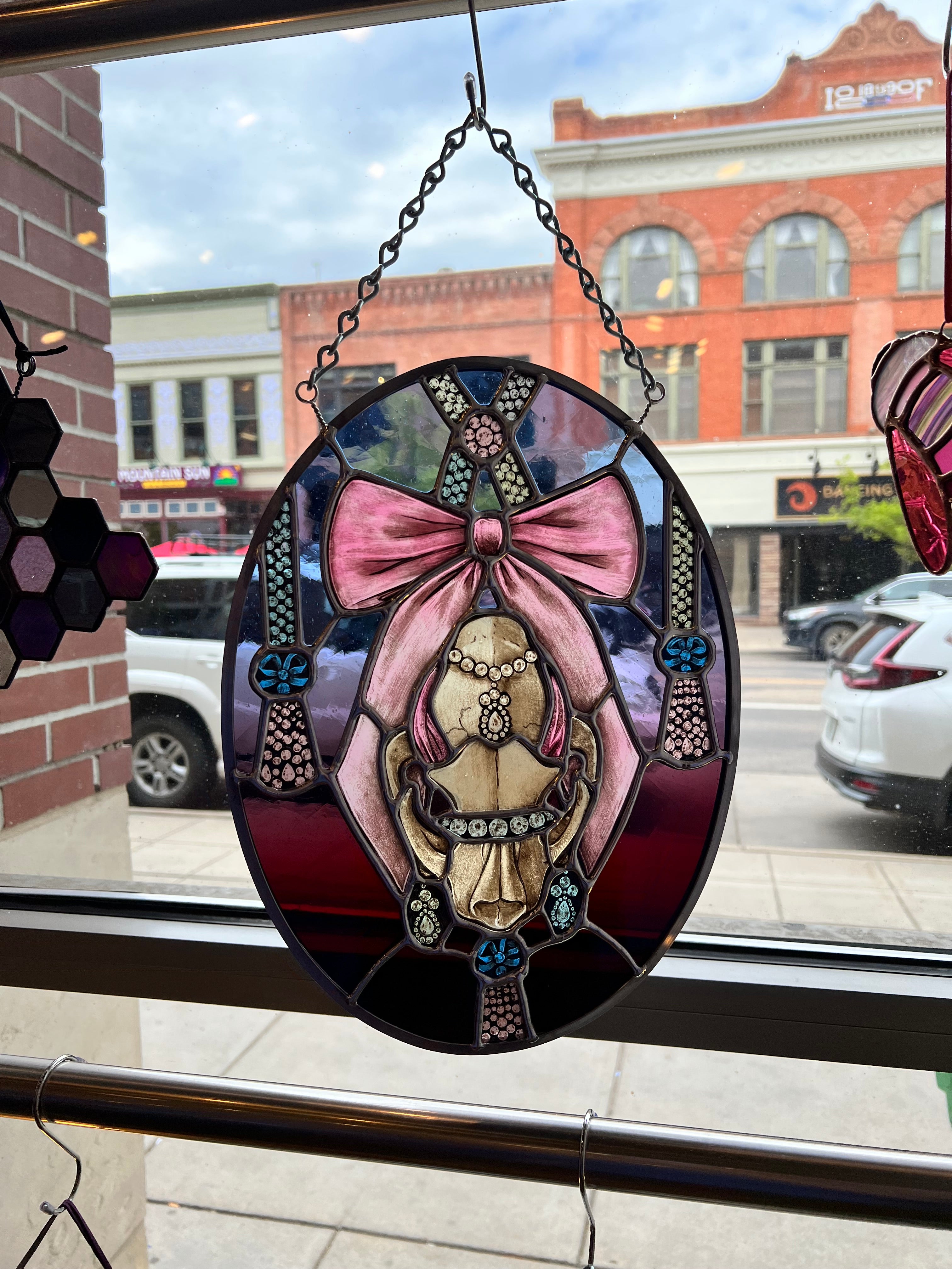 A painted stained glass skull in an oval shape. 