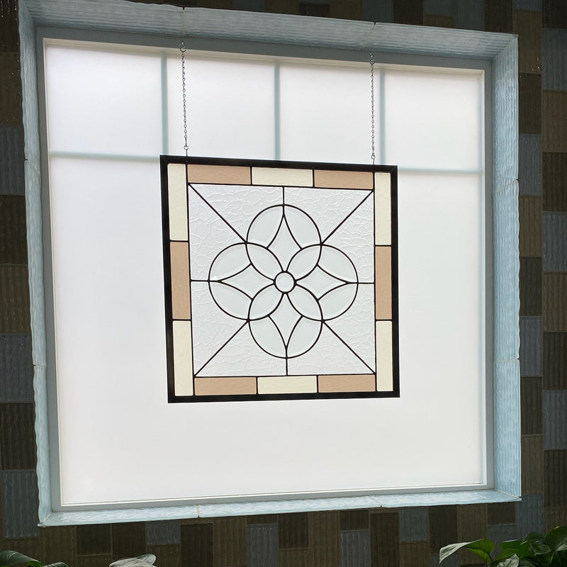 Decorative stained glass panel on a window with plants and a frog figurine below.