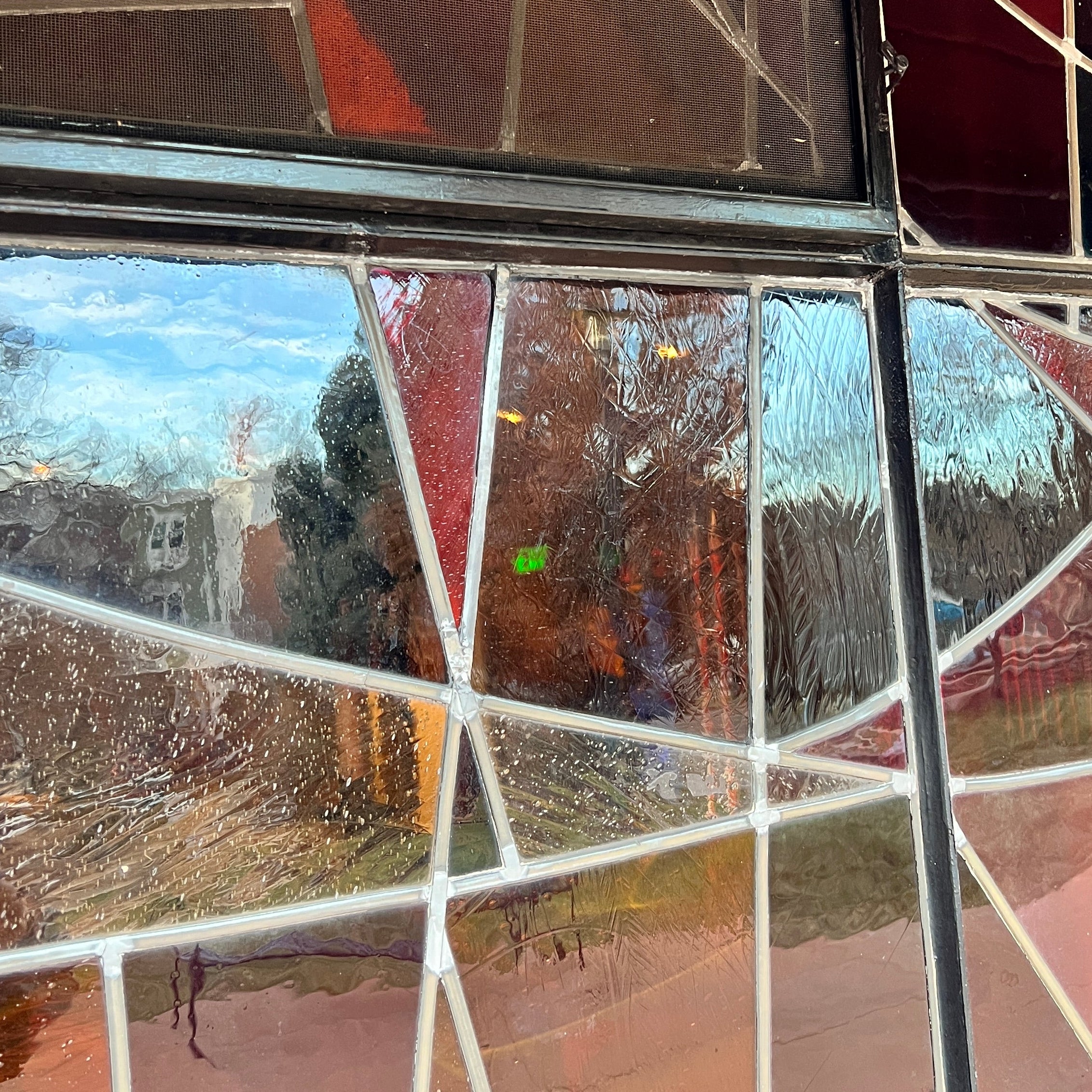 Stained glass window with geometric pattern and reflections