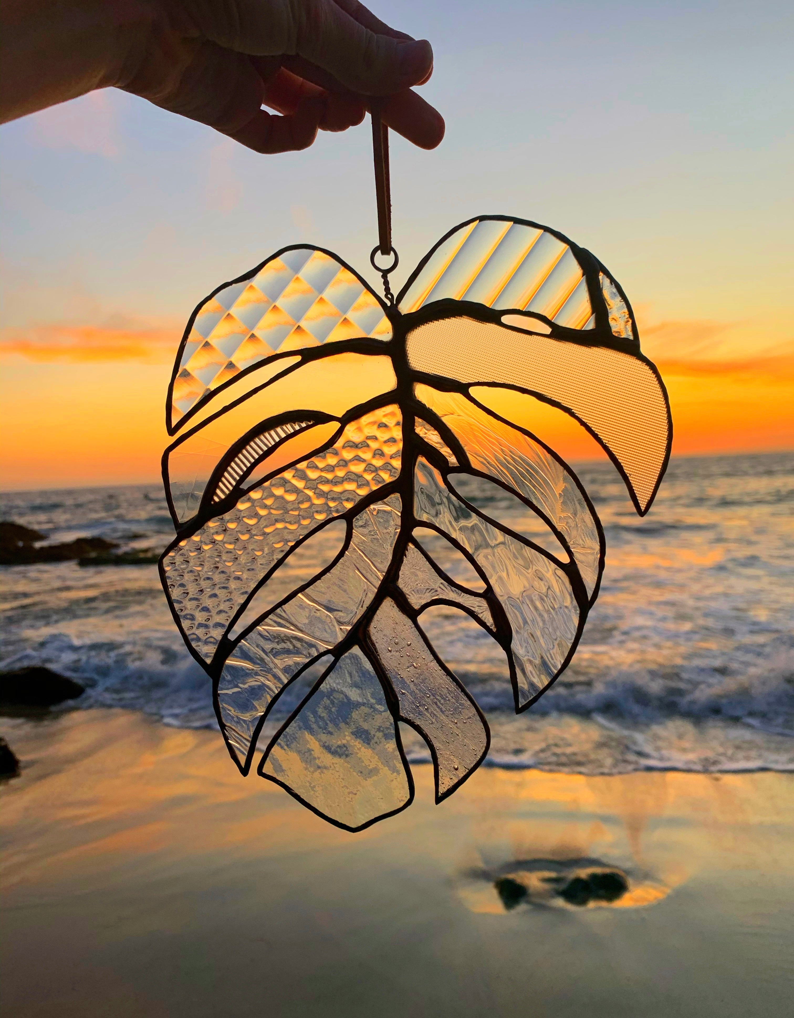 Stained glass leaf with clear glass and a beach in the background