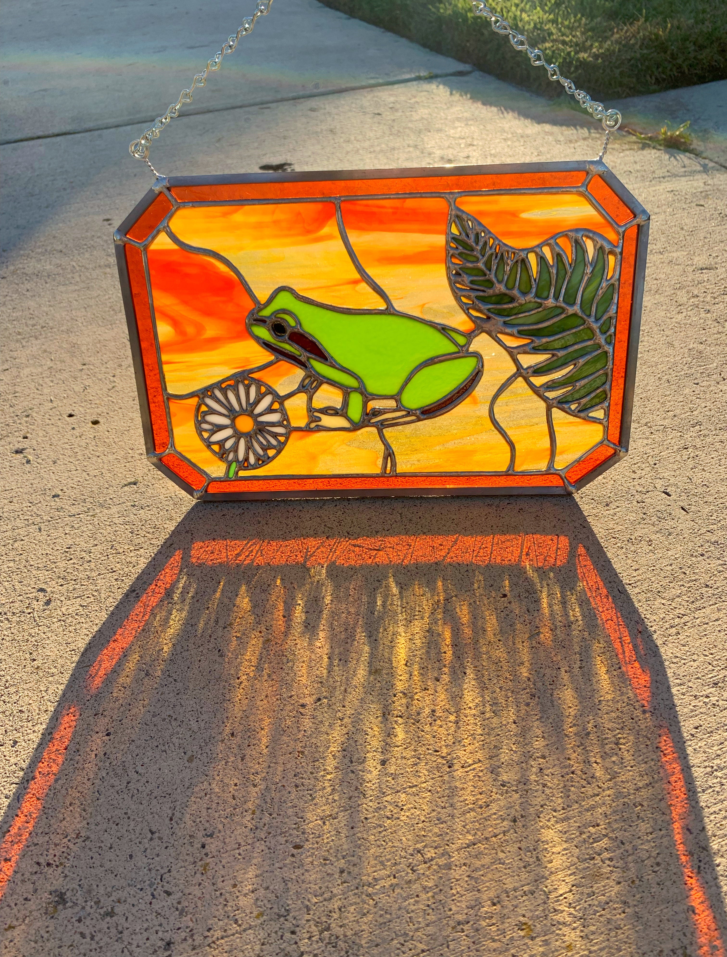 Stained glass frog with an orange background
