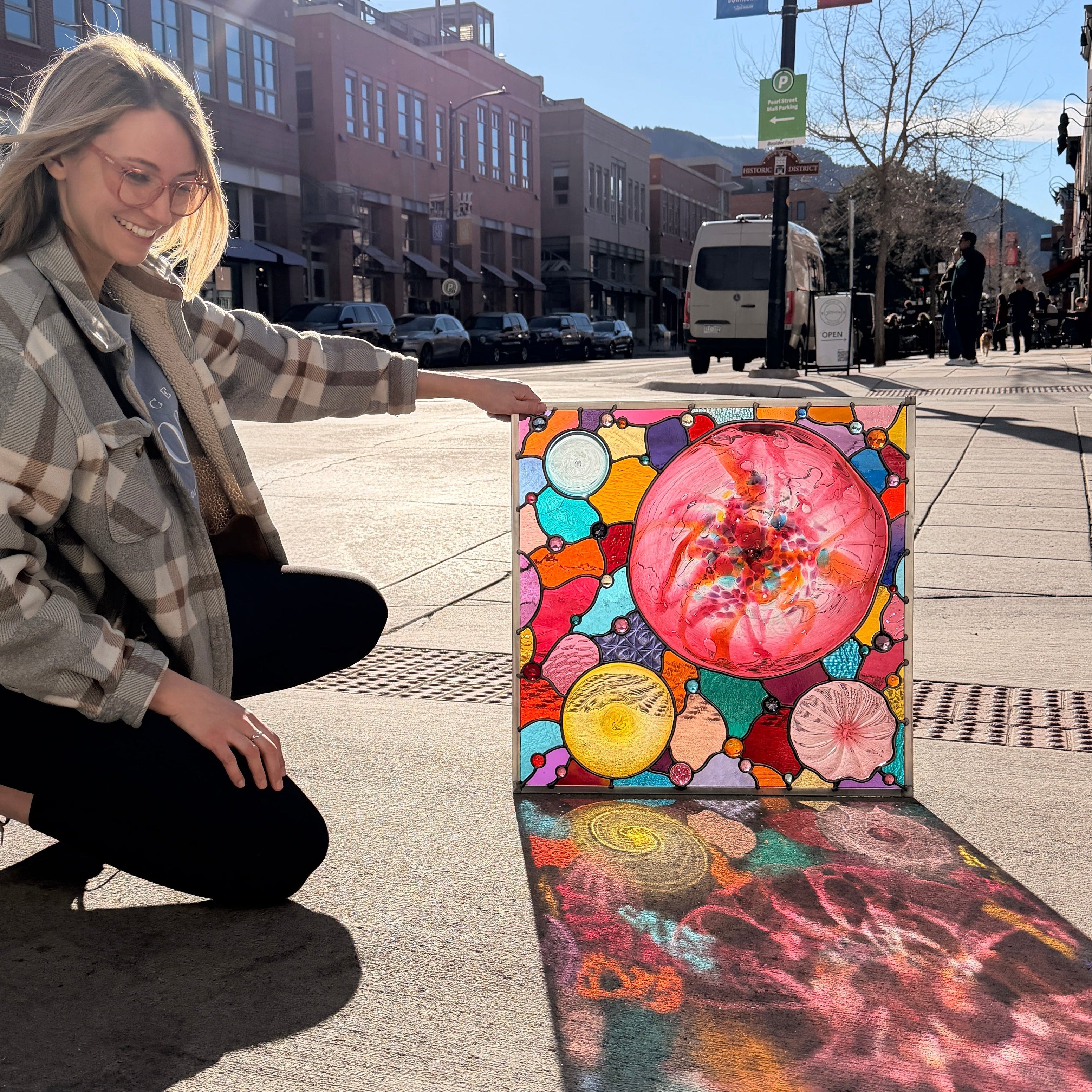 Person holding a colorful abstract painting on a city street