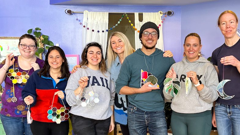 Photo of workshop participants all holding up their stained glass creations