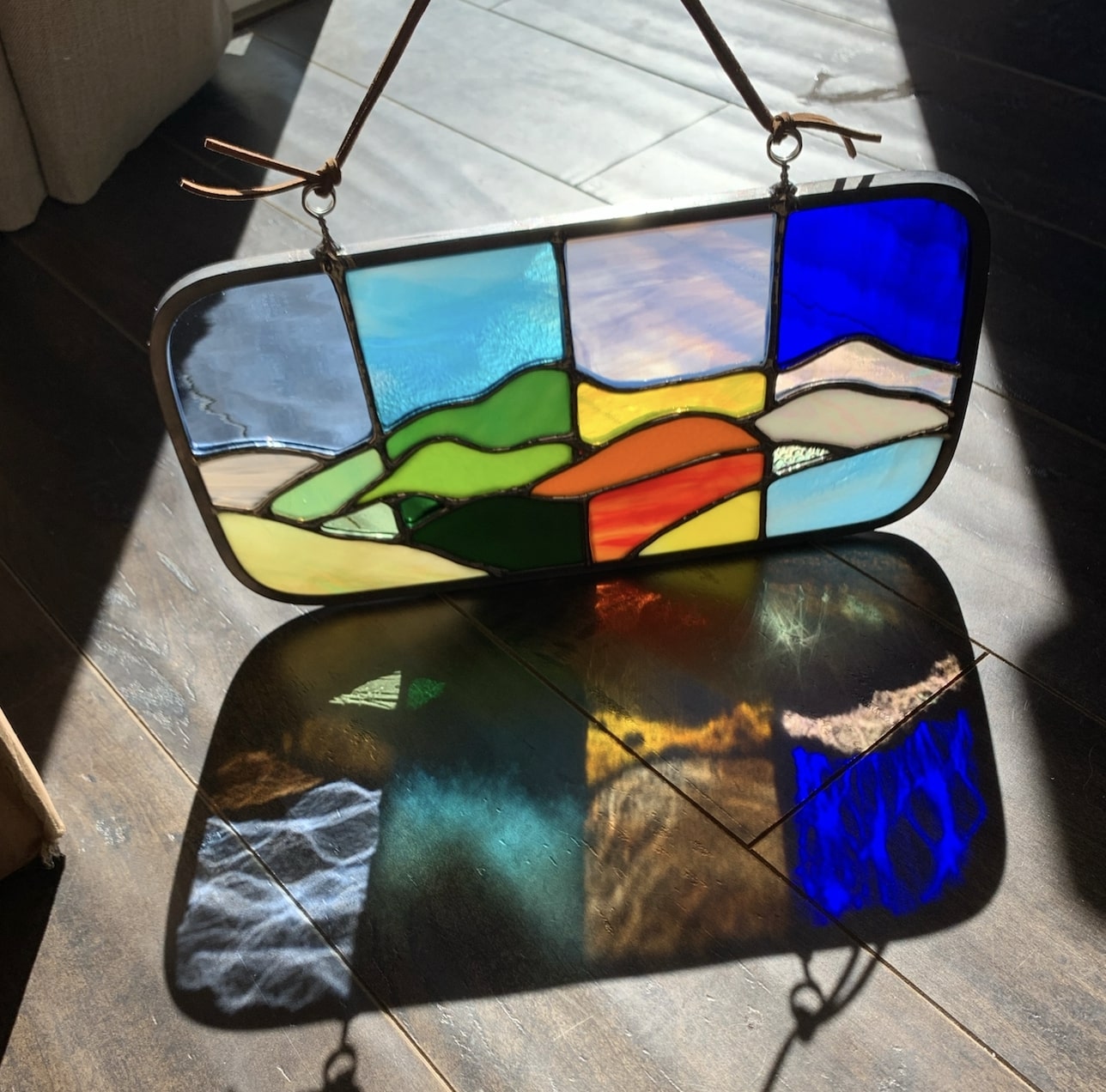 Stained glass mountainscape with refractions of the glass on the ground