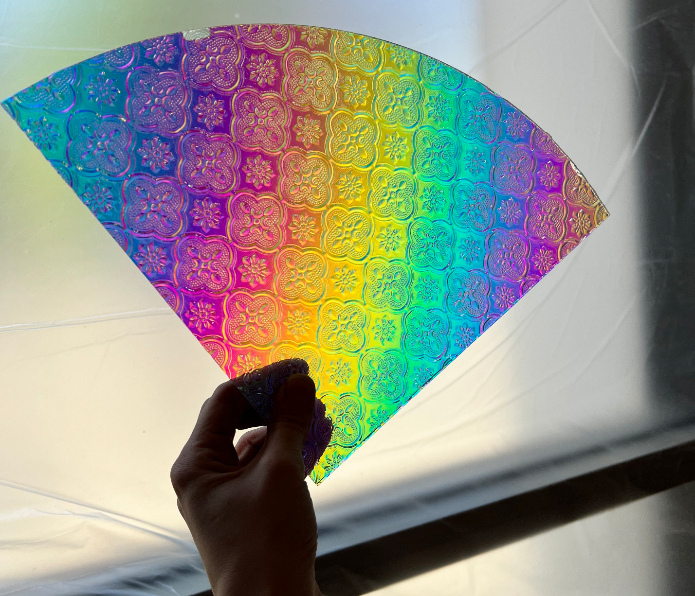 Photo of a rainbow piece of sheet glass with a textured print on it